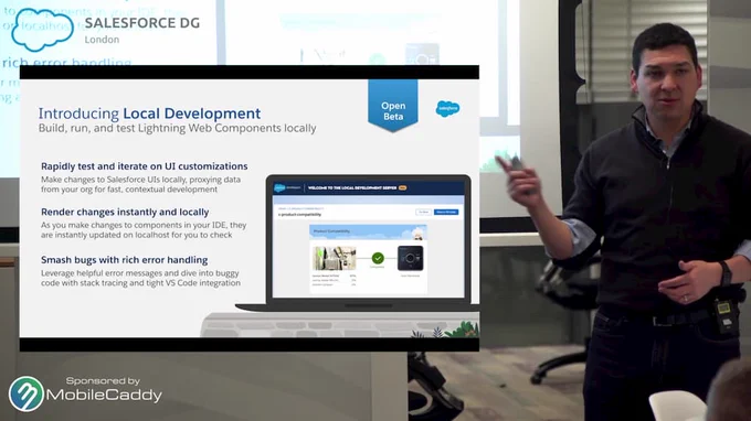 Kris Gray standing at the front of a presentation room, in front of slides. He's pointing to a screen that describes Local dev for Lightning Web Components.