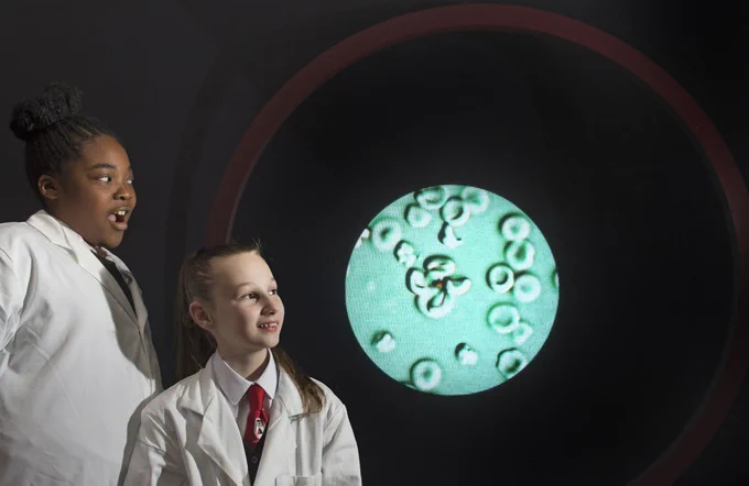 Two teenage children wearing lab coats