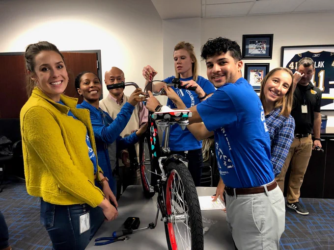 group of employees smiling and building a bike