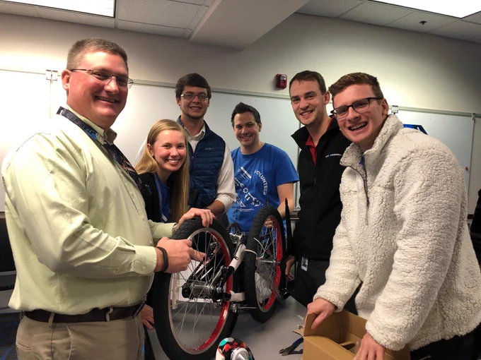 group of employees smiling and building a bike
