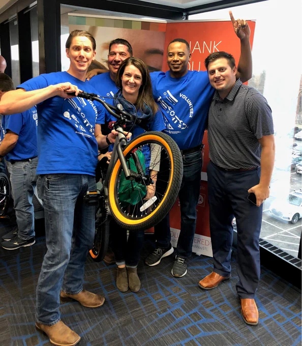 5 employees holding up a bike