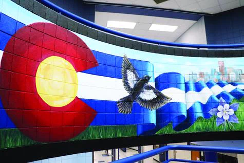 A curved mural, featuring the Colorado flag, spooling out, with the Denver skyline behind and a columbine flower in front.
