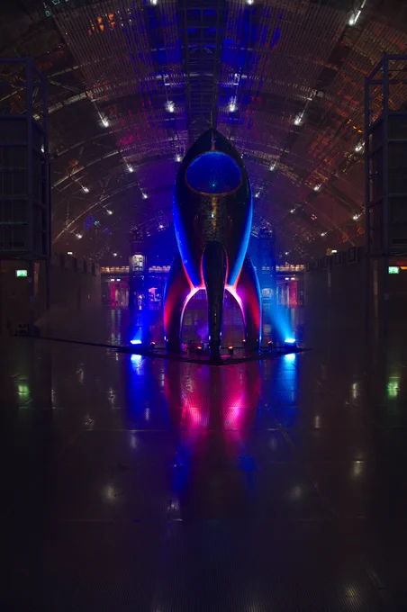 A picture of the Fairydust standing in the glas hall during 36C3 at night, lit up with blue and red LED spots.