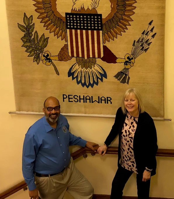 US Consulate General Peshawar and Director General indoors standing in front of banner with eagle