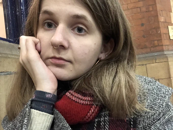 Katie, a young woman with mid length dark blonde hair, is looking tired and fed-up, and has her chin resting on her hand.