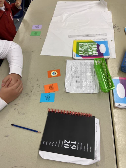 Students around table with mathops game cards as they calculate an answer