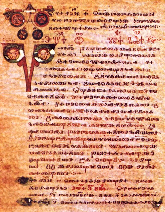 A leaf of parchment showing rounded Glagolitic letters. The drop cap letters at the section beginnings are decorated with patterns and illustrations of faces.