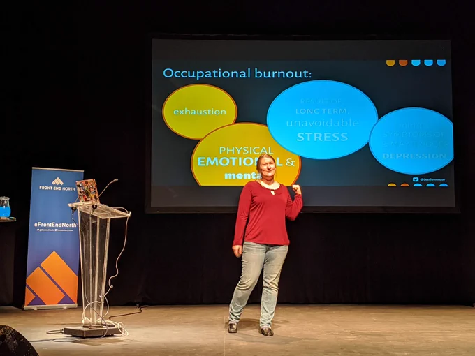 Jessica on stage with slides showing info about occupational burnout.
