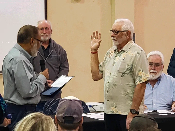A swearing-in ceremony occurs inside a gym. Individuals stand in the background.