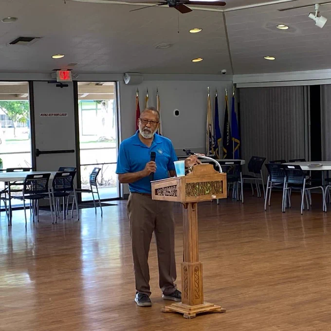 Speaking at a podium with a microphone.
