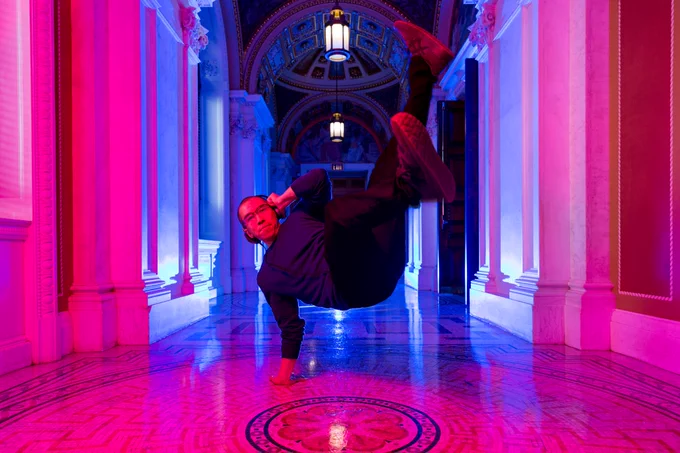 Man dancing in hallway. Supporting his entire body in the air with only one hand on the ground.