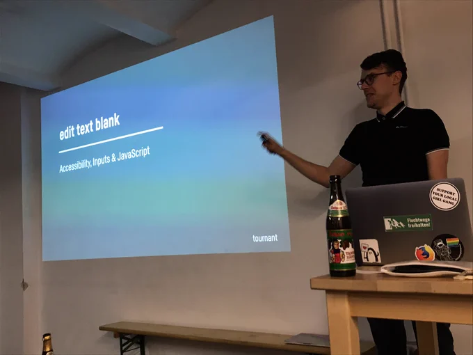 Oscar standing in front of a slide that says “edit text blank: Accessibility, inputs & JavaScript”.