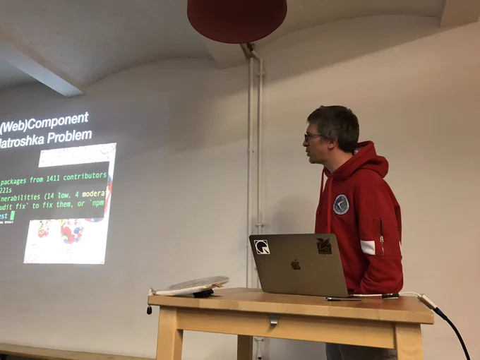 Sebastian presenting and turning towards the screen to show some code on a slide.