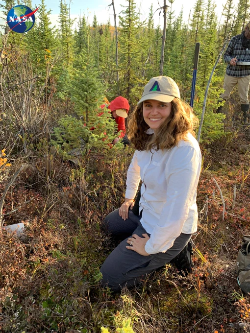 Liz Hoy kneeling in a field of sphagnum wearing an ABoVE baseball cap