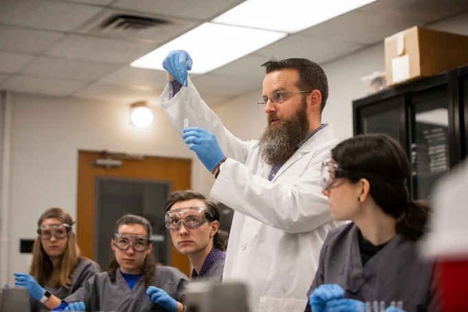dr. lou hirsch holding up test tube in front of students