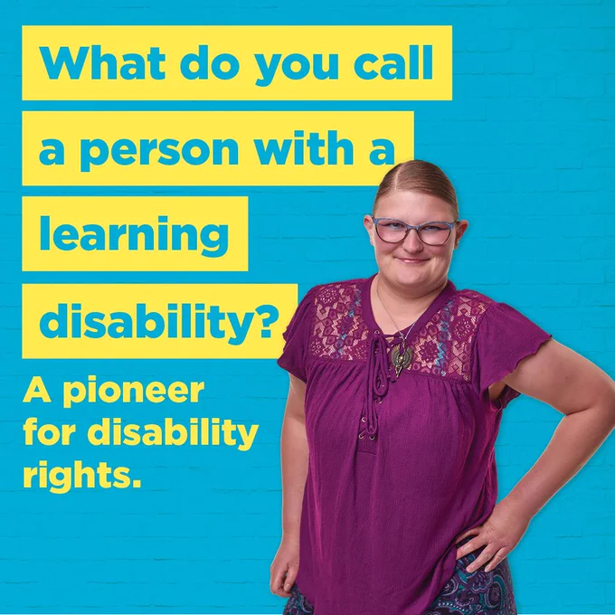 [Image Description: a young woman stands with her hand on her hip in front of a bright blue background. She is wearing a purple shirt with lace inserts and a paisley shirt. She is smiling confidently with her mouth closed. Highlighted in yellow text is "What do you call a person with a learning disability? A pioneer in Indiana disability rights."]