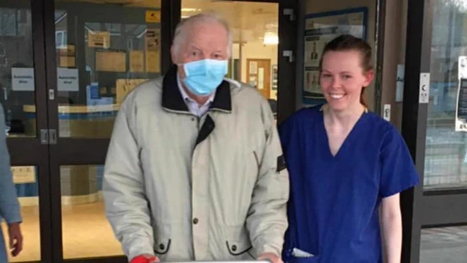Grandfather Ewart leaving hospital arm-in-arm with a smiling NHS nurse.