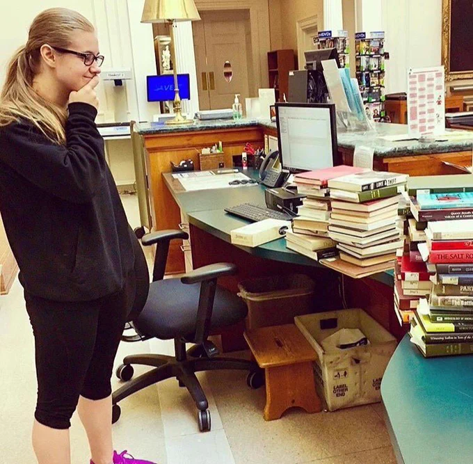 Woman looking at stack of books