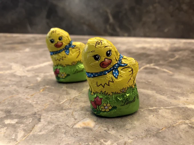 Two small Easter chocolate chickens on a bench.