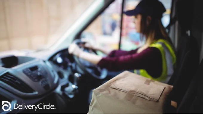 a female delivery driver sitting in her van with packages in the seat beside her
