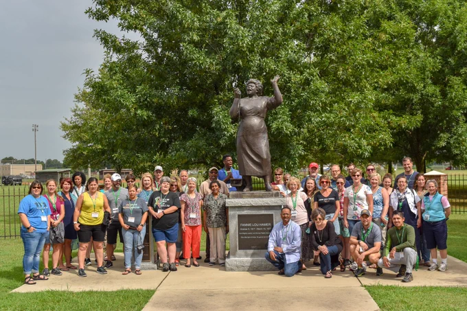 A group of teachers stand around the Fannie Lou Hamer statue as part of a Delta State University immersive summer program.