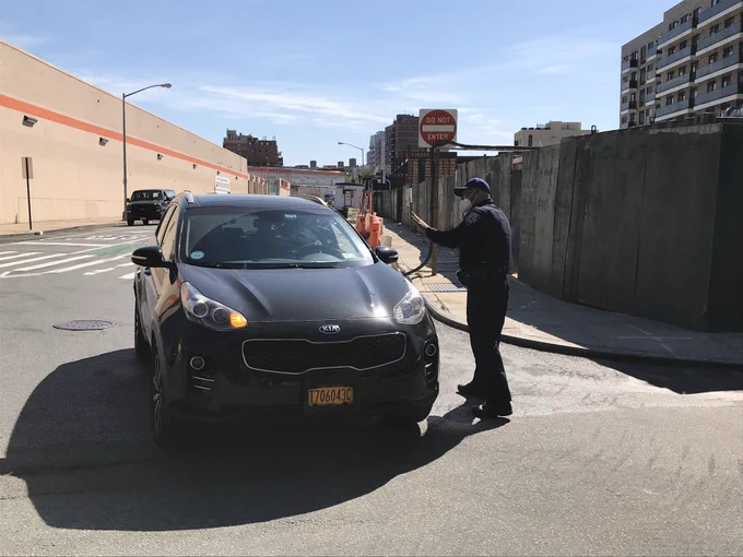A dark-colored for-hire vehicle on line, as well as a TLC officer.