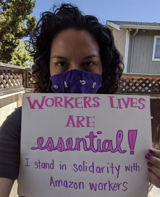 Person holding a sign that reads: Worker's lives are essential! I stand in solidarity with Amazon workers. 