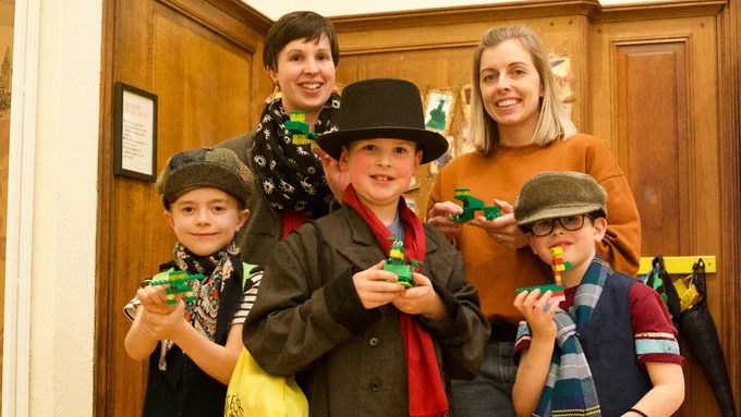 Two mothers and three boys hold their Lego dinosaur creations at the Andrew Carnegie Birthplace Museum.
