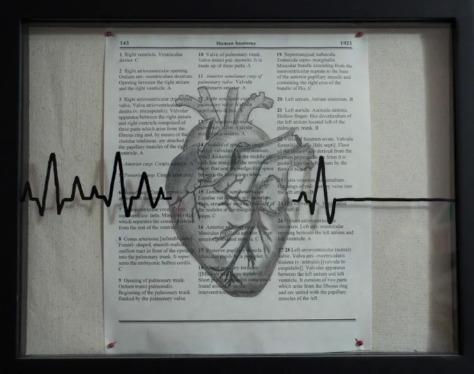 A heart is drawn in charcoal on a textbook page and framed in a black frame.