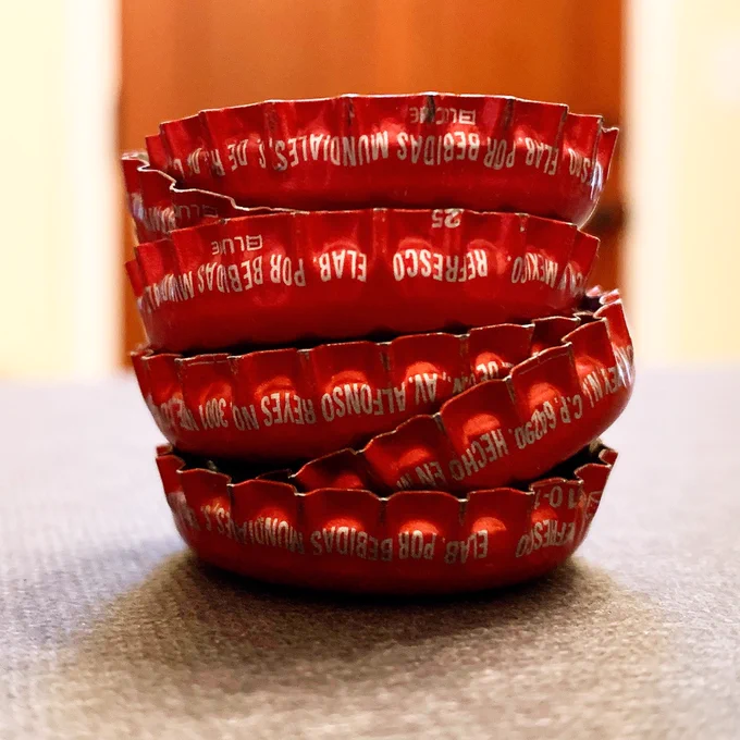 Stack of red metal bottle caps from Mexican Coca Cola bottles