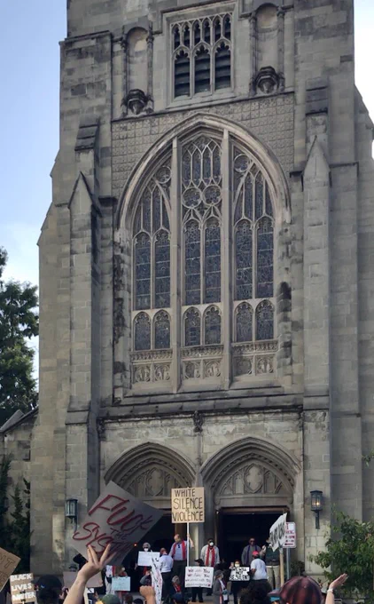 Church with protesters outside and people inside ringing bells in support
