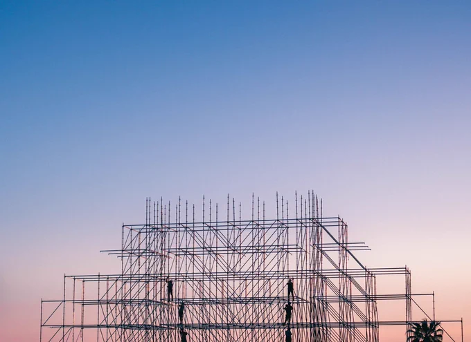 Steel framework of building under construction in front of a sunset