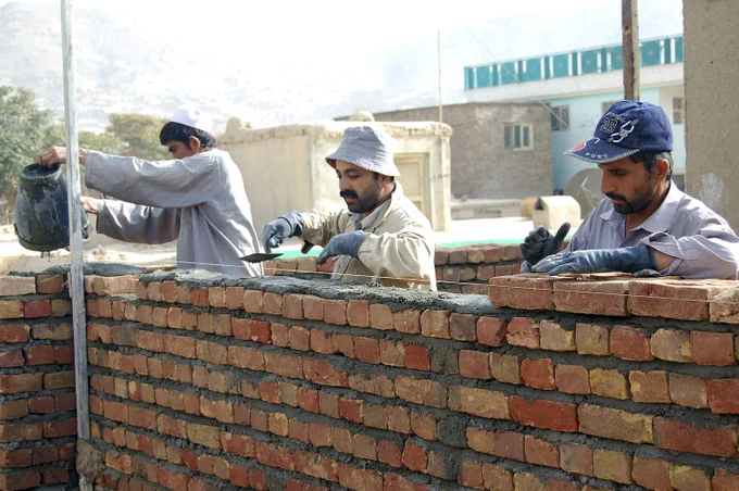 Two men and a male teenager laying the bricks of a construction project in Afghanistan. UN Photo by Jawad Jalali