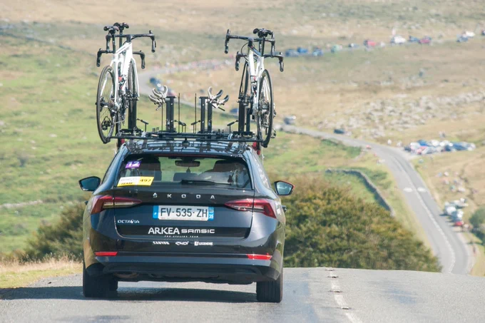 A car driving down a road. In the background is a view over Dartmoor.