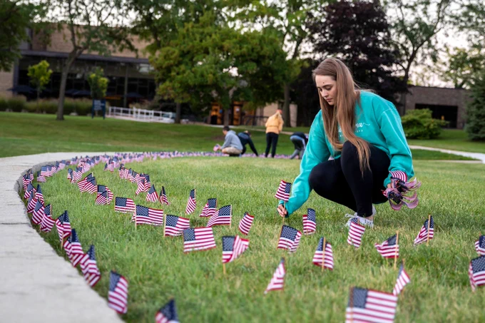A student kneels down to place flags in the lawn