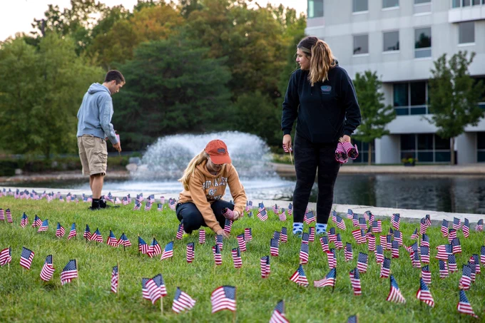 Three students place flags in the lawn near Zumberge Pond.