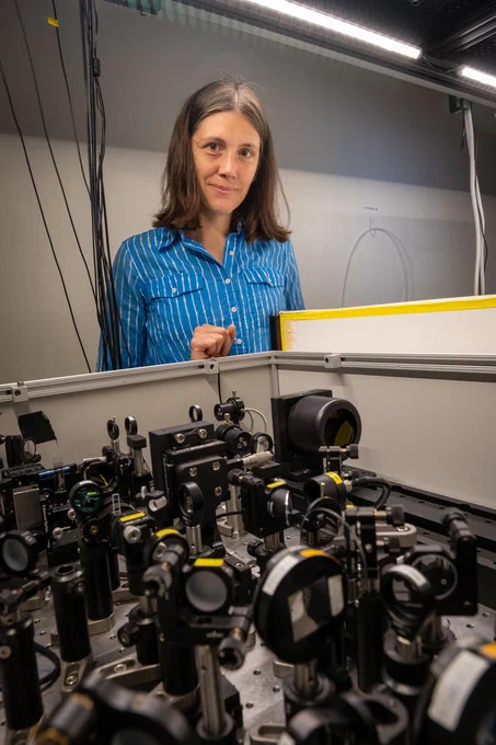 Photo of a white woman standing behind some complex equipment