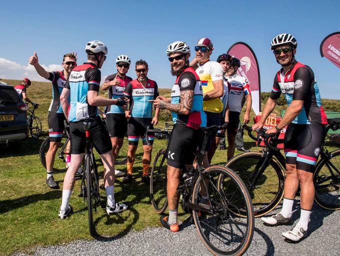 A group of cyclists smiling at the camera waiting for the peloton to arrive 