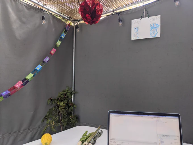 Laptop with RStudio open, on table with Lulav and Etrog, in a Sukkah