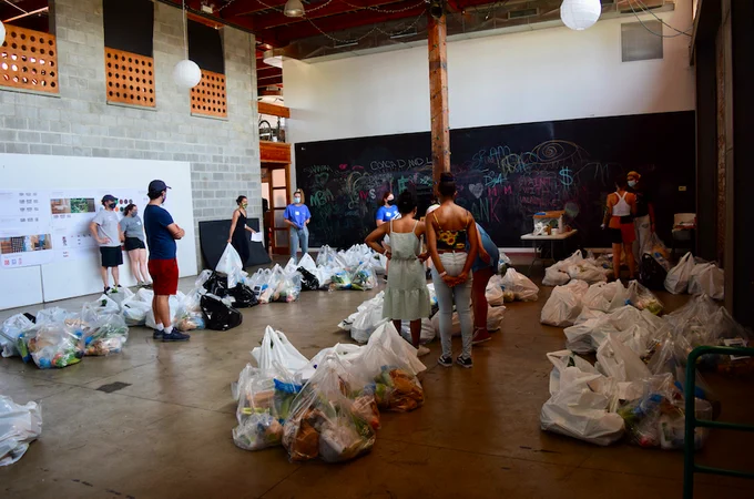 Ten volunteers listen to their driver instructions, surrounded by bags of local food ready to deliver
