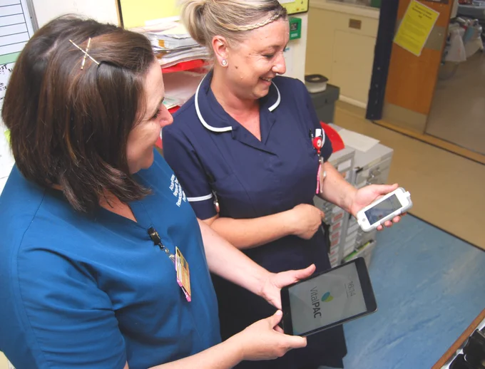 Two nurses are looking at mobile phones