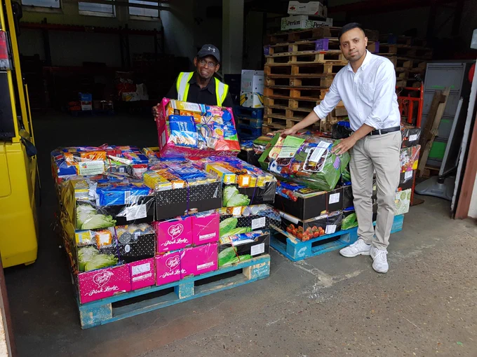 Image shows a photo of Eric Samuel and Afzal Hussain, Community Food Enterprise warehouse with food supplies in warehouse of Tate and Lyle, who let them use space for free. Image copyright ExCeL London