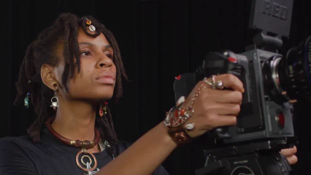 a young Black woman operates a film camera