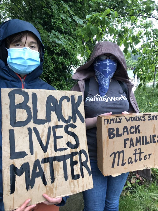 Two FamilyWorks employees wearing masks holding cardboard signs that say “Black Lives Matter” and “FamilyWorks Says Black Families Matter” in bold black letters.