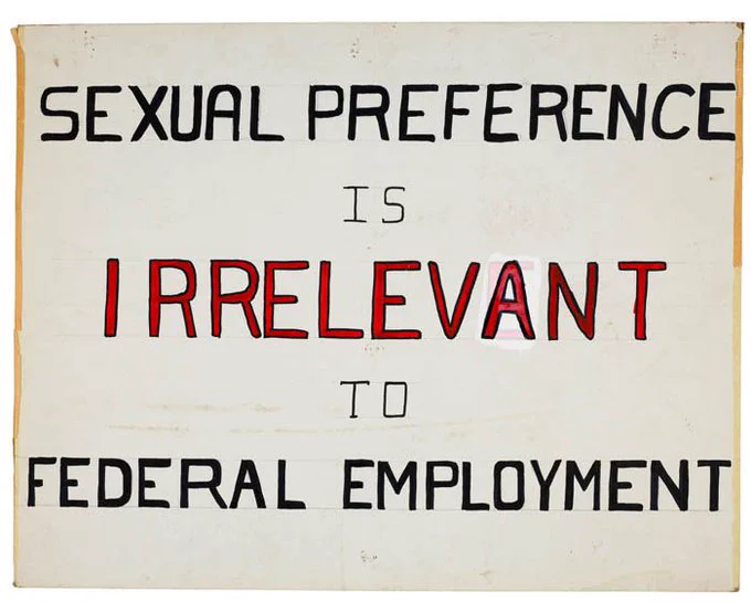 A protest sign that reads "Sexual preference is irrelevant to federal employment."