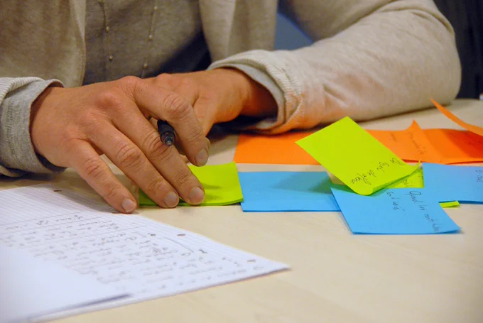 main tenant un stylo en train d'écrire sur des post-it