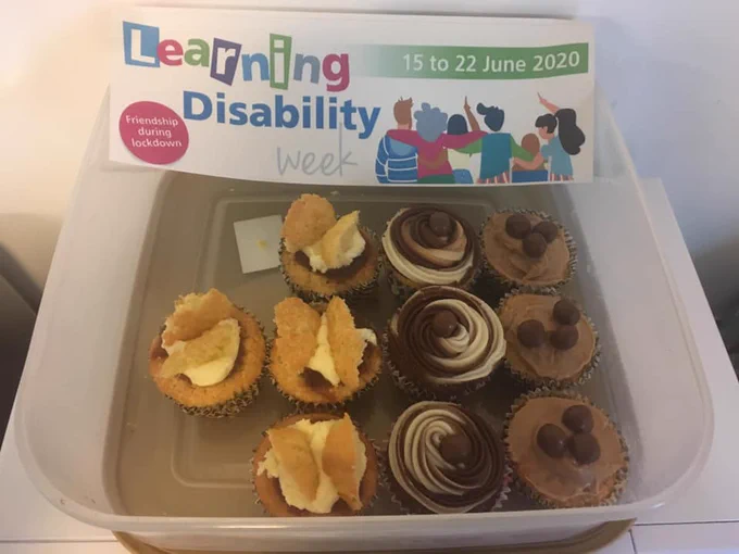 A box of assorted cupcakes, with a 'Learning Disability Week' flyer next to them