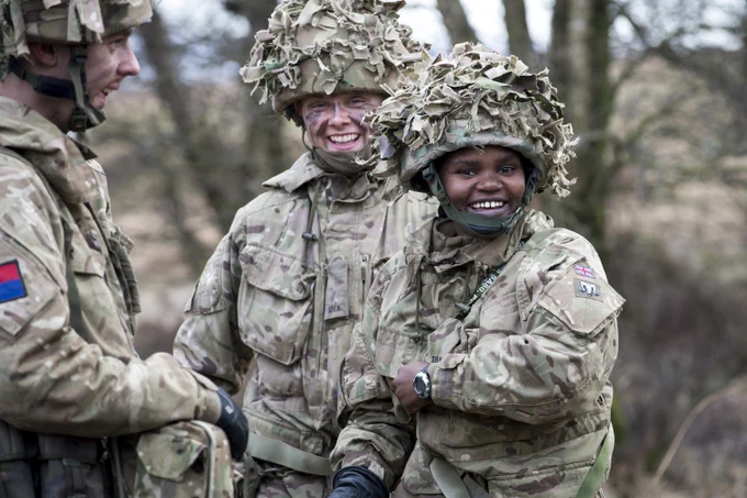 Three soldiers share a joke, two look to the camera and smile.