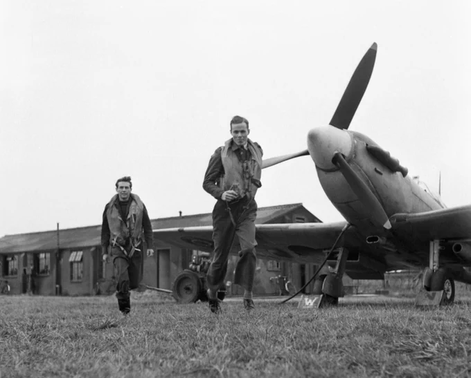 2 young pilots run to their Spitfires
