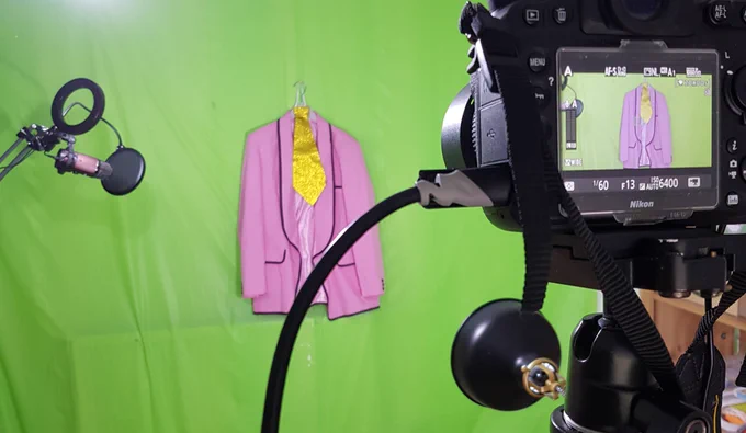 A camera pointed at a pink jacket against a green screen